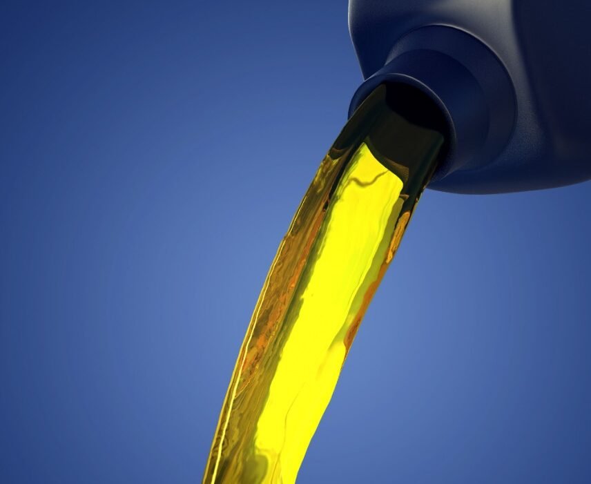 Golden oil flows smoothly from a dark bottle against a vibrant blue background, conveying a sense of purity and precision in motion.