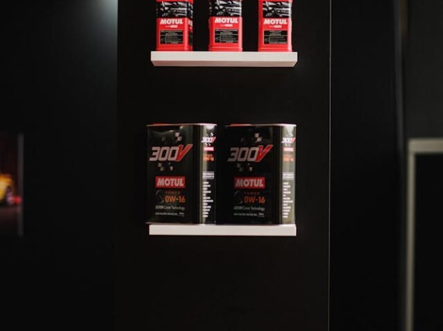 Black portfolio display with red Motul spray bottles on top shelf and two 300V cans on middle shelf. Minimalist design conveys sleek, professional feel.